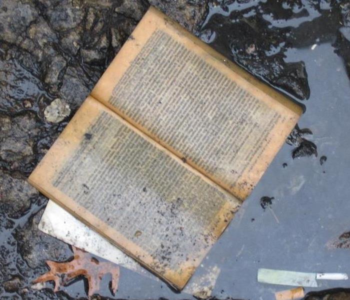 An open book submerged in a puddle and dirty.