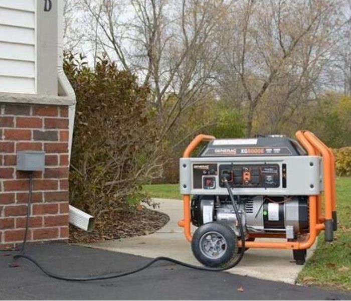 A generator is plugged into an outdoor outlet on a house