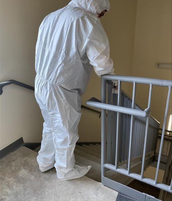 SERVPRO employee cleans stairwell banister at Denton business. 